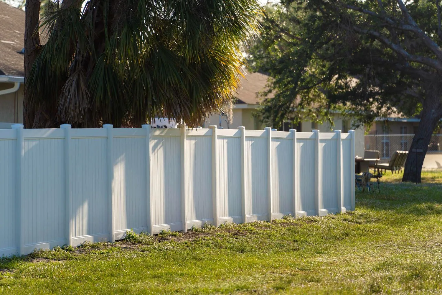 White vinyl privacy fence along a backyard lawn